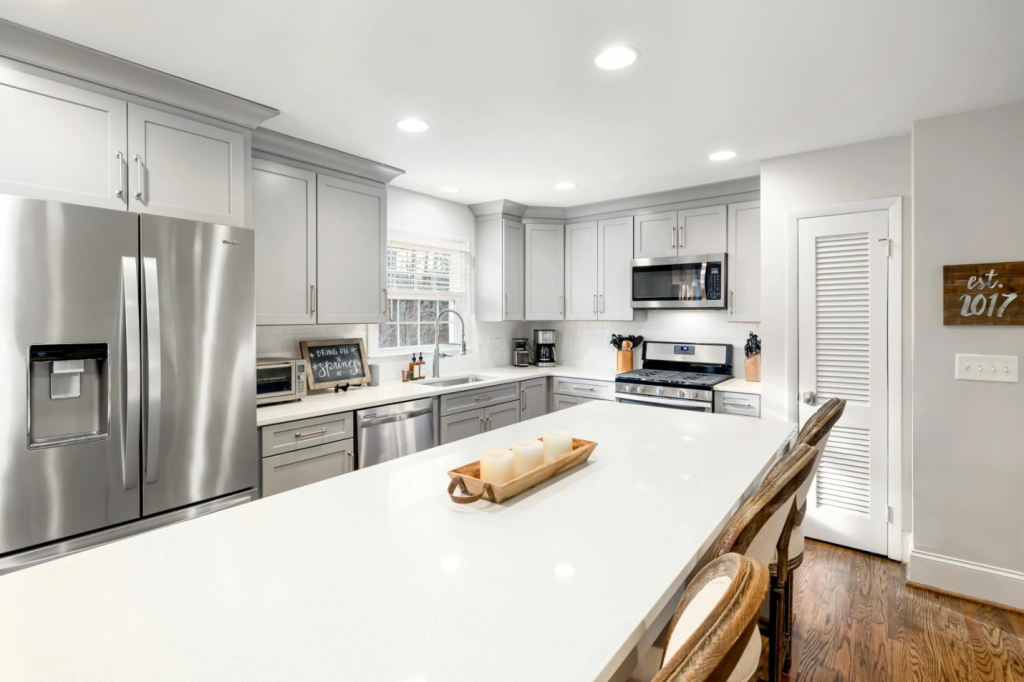 A spacious kitchen dominated by a large, pristine white countertop