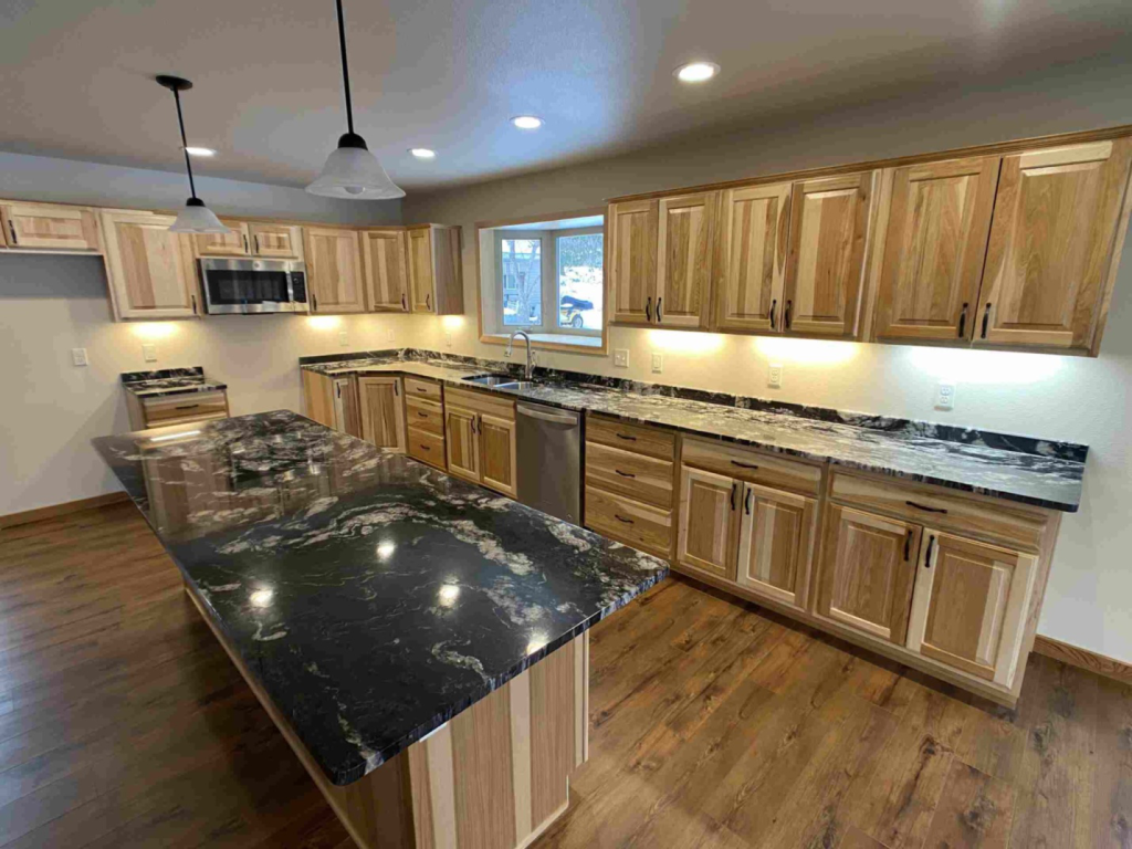 A large wooden kitchen space can be seen with black countertops