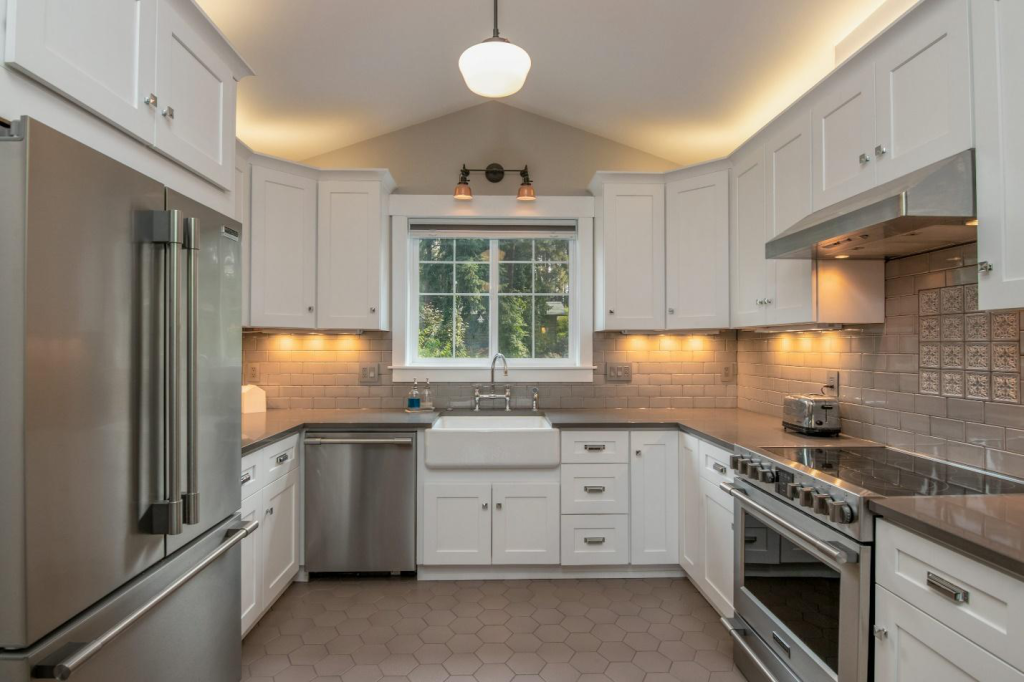 A modern kitchen with white cabinetry and steel appliances.