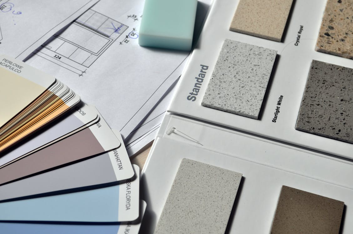 Home renovation planning materials with color swatches, countertop samples, and blueprints for budget-friendly home additions.