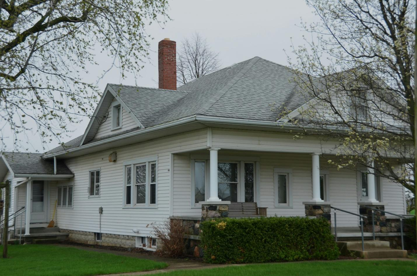 A white colored house surrounded by a manicured lawn.