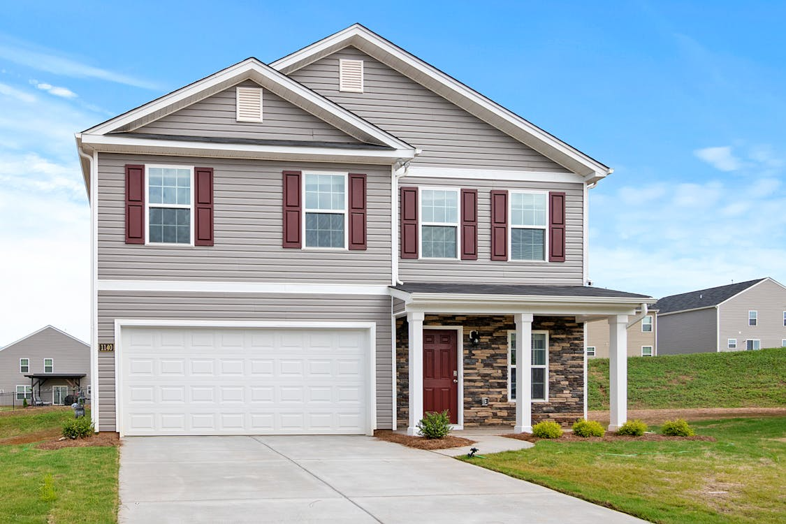 An image of a house with a white garage door and a long driveway